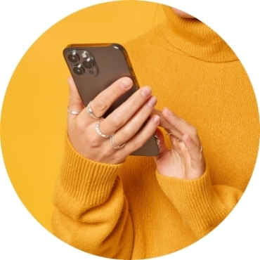 Person in orange sweater holding an Iphone